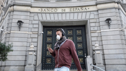 Un hombre con una mascarilla pasa junto a las oficinas del Banco de España, en Barcelona. REUTERS/Nacho Doce