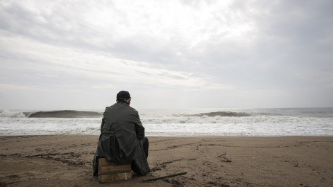 Hombre mirando el mar en una playa con cielo nublado. Imagen de archivo / Pixabay