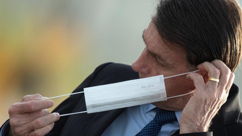 El presidente de Brasil, Jair Bolsonaro, se pone una mascarilla durante una ceremonia oficial, el 9 de junio de 2020, en el Palacio do Alvorada. EFE/ Joédson Alves.