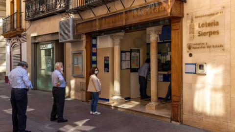 Varias personas hacen cola en la puerta de una administración de Loterías en la calle Sierpes de Sevilla. /EFE