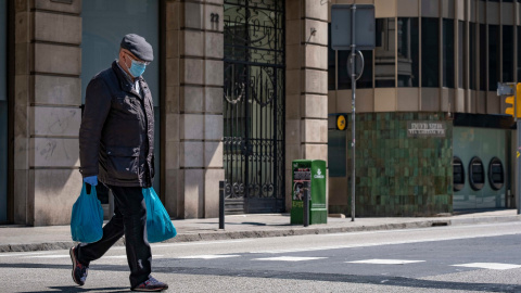 Un home que porta borses de la compra camina en la deserta Via Laietana causa de les mesures de confinament. Foto: Paco Freire/SOPA/ DPA/ Europa Press