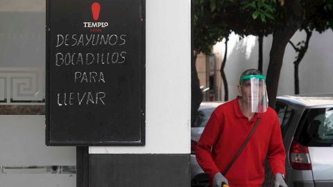 Un trabajador protegido con una máscara reparte en un bar de Córdoba. EFE/Rafa Alcaide/Archivo