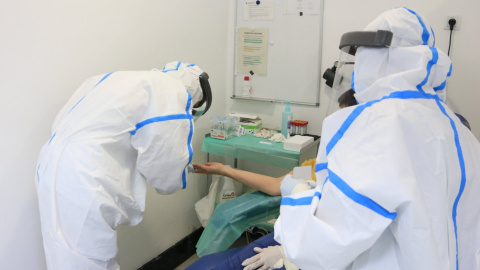 Professionals del CAP Manso, amb equip de protecció individual (EPI), en el moment d'extreure una mostra de sang amb una punxada al dit a una participant a l'estudi de seroprevalença del coronavirus a nivell estatal. 30 d'abril del 2020. (Horitzontal)