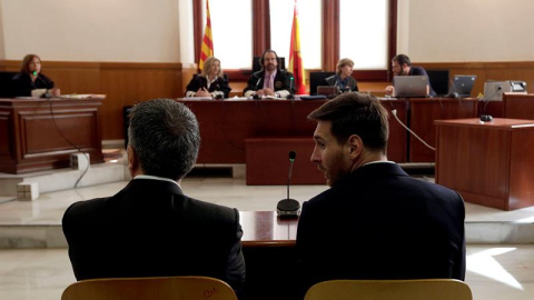 El jugador del FC Barcelona Lionel Messi y su padre, Jorge Horacio Messi, en la sala de la Audiencia de Barcelona durante la tercera jornada del juicio que se sigue contra ellos por tres delitos contra la Hacienda Pública. EFE/Alberto Estévez