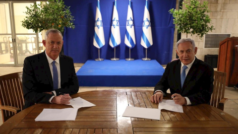 20/04/2020.- El primer ministro israelí, Benjamín Netanyahu (d), firma junto al centrista Beny Gantz (i) el acuerdo alcanzado este lunes mediante el cual Netanyahu seguirá siendo jefe de Gobierno israelí durante el primer año y medio de Ejecutivo uni