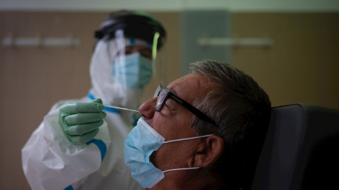 Una profesional sanitaria realiza una prueba PCR a un paciente. EFE/Enric Fontcuberta