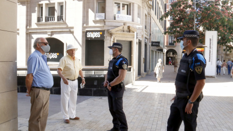 Dos agents de la Guàrdia Urbana parlen amb dos homes a Lleida, un amb mascareta i l'altre sense. ACN