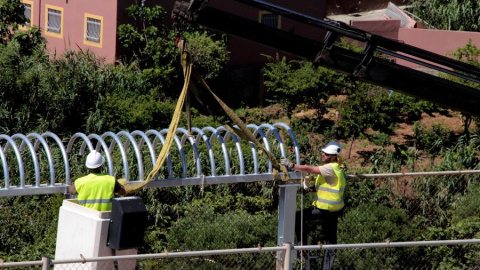 El personal encargado de las obras de reforma del perímetro fronterizo que separa Ceuta de Marruecos instala los primeros tubo antitrepados que sustituyen a las concertinas que coronaban el vallado fronterizo. EFE/ Reduan Dris