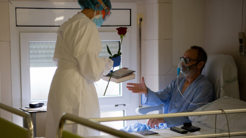 Una professional de l'Hospital Clínic lliura a un pacient ingressat una rosa i un llibre per Sant Jordi, en la pandèmia de coronavirus. Francisco Ávila / Hospital Clínic