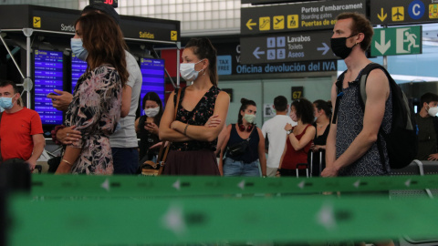 Diversos passatgers de l'aeroport del Prat amb mascaretes fent cua per facturar l'equipatge en el dia de la reobertura de la T2. GEMMA SÁNCHEZ / ACN