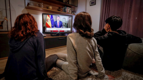 Tres jóvenes ven el discurso extraordinario del rey Felipe VI, en un mensaje por televisión dirigido a los españoles en relación con la crisis del coronavirus. EFE/José Manuel Vidal