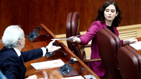 La presidenta de la Comunidad de Madrid, Isabel Díaz Ayuso, entrega un papel al consejero de Sanidad, Enrique Ruiz Escudero, durante la sesión de control al ejecutivo regional en la Asamblea de Madrid. E.P./Pool