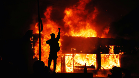 Un manifestante delante de una edificio ardiendo durante los disturbios desatados en Minesota tras la muerte de George Floyd, un ciudadano negro, a manos de la policía.- REUTERS