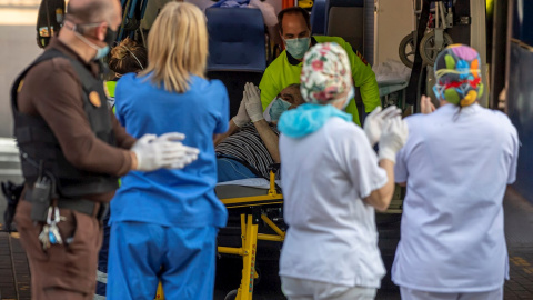 Un paciente que baja de una ambulancia participa en el apluaso al personal sanitario y de seguridad del hospital Virgen de la Salud de Toledo este domingo. Los sanitarios han agradecido el apoyo de los ciudadanos que se han acercado convocados a través d