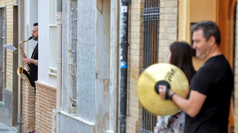 Varios músicos se asoman al portal de sus casas en el barrio de Benimaclet (València) para interpretar 'Paquito el Chocolatero' y 'Amparito Roca'./ Kai Försterling (EFE)