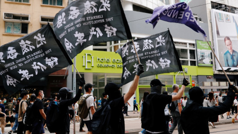 Unos manifestantes sostienen una bandera de independencia de Hong Kong mientras marcha contra la ley de seguridad nacional. REUTERS / Tyrone Siu