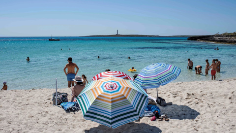 Varias personas disfrutan del buen tiempo durante el primer día de verano y primer día de la nueva normalidad en la playa de Punta Prima, Menorca. EFE/ David Arquimbau Sintes