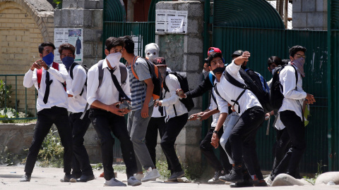 Estudiantes con el rostro cubierto lanzan piedras contra la policía india durante las priotestas en el estado de Cachemira. REUTERS/Danish Ismail