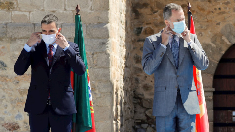 01/07/2020.- El presidente del Gobierno, Pedro Sánchez (i) y el rey Felipe VI (d) se ponen las mascarillas antes de la foto oficial en la explana del castillo de Elvas durante el acto oficial de la reapertura, tras tres meses y medio cerradas por el coro