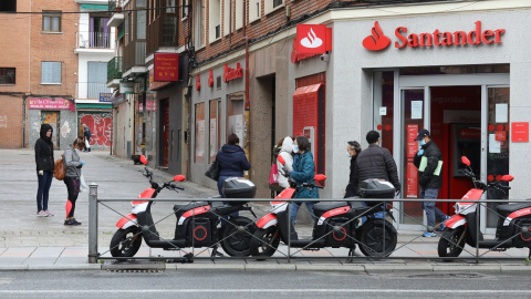 Varias personas esperan para entrar a una oficina del Banco Santander durante el estado de alarma, en Madrid. E.P./Marta Fernández