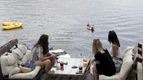 Varias personas disfrutan del aperitivo en el chiringuito La Martuka, hoy domingo en el madrileño pantano de San Juan, en un día soleado y con altas temperaturas. EFE/J.J. Guillén