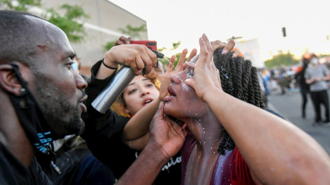 31/05/2020.- Un manifestante se limpia los ojos tras ser rociada con un spray por la policía durante las manifestaciones por quinto día consecutivo por la muerte de George Floyd en Minneapolis, Minnesota, Estados Unidos este domingo. EFE/ Craig Lassig