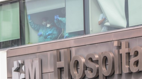 Sanitarios del Hospital de La Paz totalmente protegidos saludan y agradecen el apoyo desde una de las ventanas del centro donde se lucha contra el coronavirus, en Madrid (España)