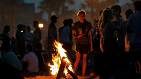 Una joven observa las llamas de la hoguera que ha encendido junto a un grupo de amigos para celebrar la Noche de San Juan | EFE