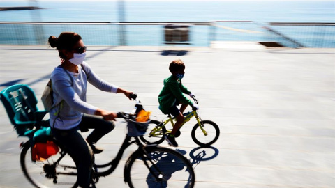 Madre e hijo en bicicleta disfrutan del día soleado en el paseo marítimo de Barcelona, este domingo en el que los menores de catorce años podrán salir a la calle por primera vez, cuando se cumple el cuadragésimo cuarto día de aislamiento social tras