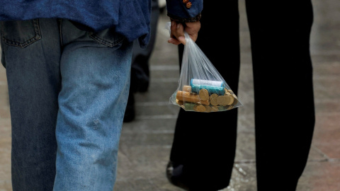 Un hombre lleva una bolsa de plástico con nuevas monedas de euro en una calle de Ronda, España, el 15 de noviembre de 2022. Foto: REUTERS/Jon Nazca