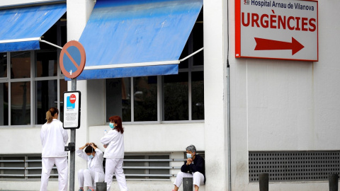 Personal sanitario del Hospital Arnau de Vilanova descansa unos minutos ante la puerta de urgencias, hoy durante el sexto día del estado de alarma decretado por el Gobierno.EFE/ Manuel Bruque