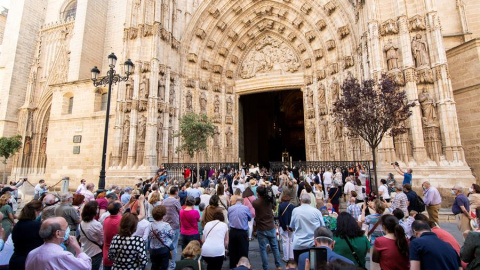 El arzobispo de Sevilla, Juan José Asenjo (c) muestra la Custodia de mano con el Cuerpo de Cristo en una de las puertas de la Catedral de Sevilla al suspenderse la procesión por las calles debido al estado de alarma por la crisis sanitaria de la covid-1