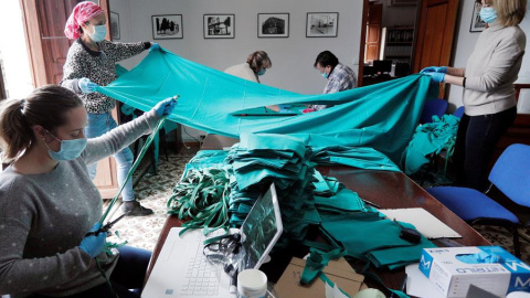 La concejala de Sanidad de Benetússer (Valencia), Aroa Juan (i), trabaja junto a otras voluntarias en las dependencias del ayuntamiento confeccionando mascarillas con material facilitado por el Hospital Peset de València, su centro de referencia, en una