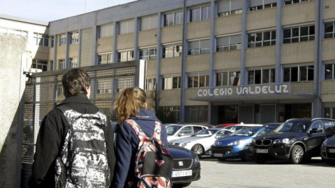 Dos jóvenes pasan por la puerta del colegio Valdeluz. /EFE