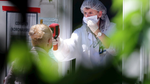 Una trabajadora sanitaria toma la temperatura a una persona. EFE/Archivo