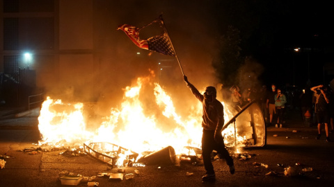 Un manifestante sostiene una bandera estadounidense quemada durante una protesta por George Floyd, en St. Louis, Missouri. REUTERS / Lawrence Bryant