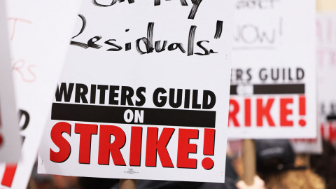 Los miembros del Writers Guild of America (WGA) East sostienen carteles mientras caminan en la línea de piquete fuera del Peacock NewFront el 2 de mayo de 2023 en la ciudad de Nueva York.- AFP