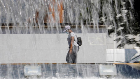 Una mujer pasa ante una fuente en Córdoba que este fin de semana registra altas temperaturas con aviso naranja decretado por la Agencia Estatal de Meteorología (Aemet). EFE/Salas