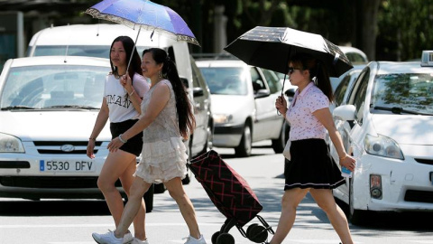 Tres mujeres se protegen del sol y del calor con sombrillas. /EFE