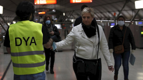 14/04/2020.- Un voluntario de la DYA realiza una entrega de mascarilla a un viajero del metro de la capital vizcaína este martes. EFE/Luis Tejido