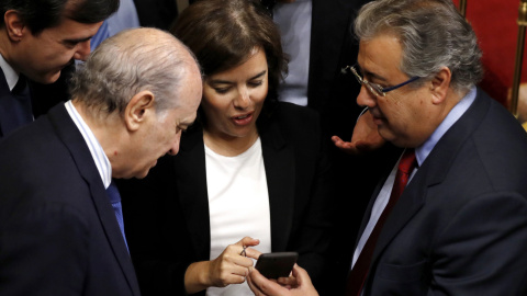 La vicepresidenta del Gobierno, Sorya Sáenz de Santamaría, conversa con el ministro del Interior, Juan Ignacio Zoido (d), y los diputados del PP Jorge Fernández Díaz (i) y José Luis Ayllón (2-i), durante un receso en el debate de las enmiendas a la 