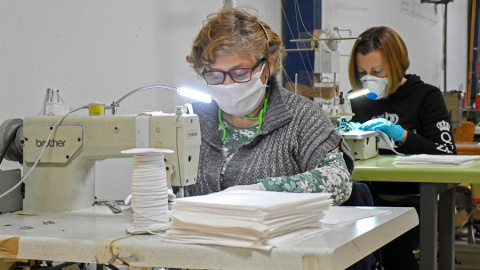 Varias mujeres fabrican mascarillas mientras colaboran de forma altruista con la empresa segoviana Mundo Laboral, que ha decidido parar la producción de su taller de confección para fabricar mascarillas | EFE