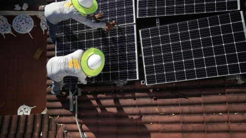 Dos operarios colocan paneles solares en el tejado de una vivienda. Foto: Joe Raedle / AFP