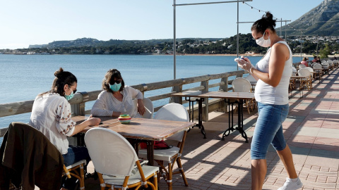 Una camarera atiende a dos clientas en una terraza en la localidad Alicantina de Denia, uno de los territorios de España que comienza la Fase 1.EFE/ Juan Carlos Cárdenas