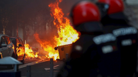 , 03/07/2020.- Agentes de la Ertzaintza observan un contenedor ardiendo en las calles de San Sebastián, donde la formación política Vox celebra esta tarde un acto electoral. EFE/Juan Herrero