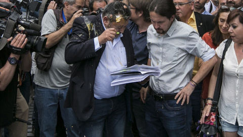 Julio Sanz,iz, presidente de la Federación Profesional del Taxi, recibe el impacto de un huevo en la cabeza mientras conversa con el líder de Podemos, Pablo Iglesias,c-d., en las proximidades de la plaza de Neptuno donde hoy el gremio de los taxistas ma