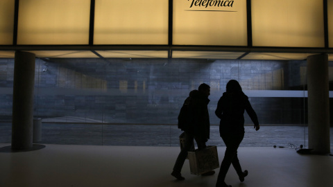 Dos personas pasan bajo el logo de Telefónica en la sede de la operadora en el distrito de Las Tablas de Madrid. REUTERS/Juan Medina