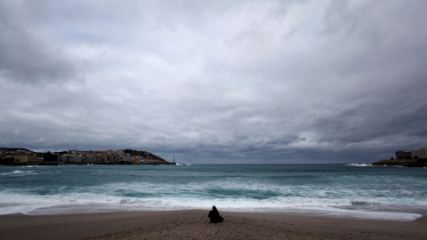 16.02.2020. Una mujer frente a la playa de Riazor de A Coruña, donde este domingo se mantiene el fuerte oleaje. EFE/Cabalar