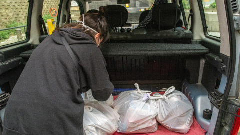 Una voluntaria carga el maletero con bolsas de alimentos básicos antes de salir al reparto entre los hogares que las necesitan.-MANU MITRU (CEDIDA)