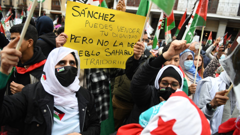 Varias personas, con banderas saharauis y una pancarta que reza 'Sánchez, puedes vender tu dignidad pero no la del pueblo saharaui', protestan durante una manifestación convocada por la Coordinadora Estatal de Asociaciones Solidarias con el Sáhara (CEA